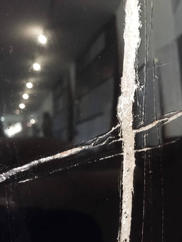 Surface noire brillante avec fissures blanches visibles