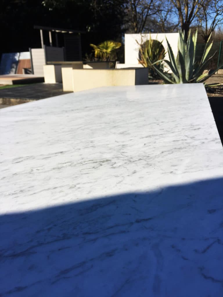 Table en marbre blanc dans un jardin ensoleill&eacute;